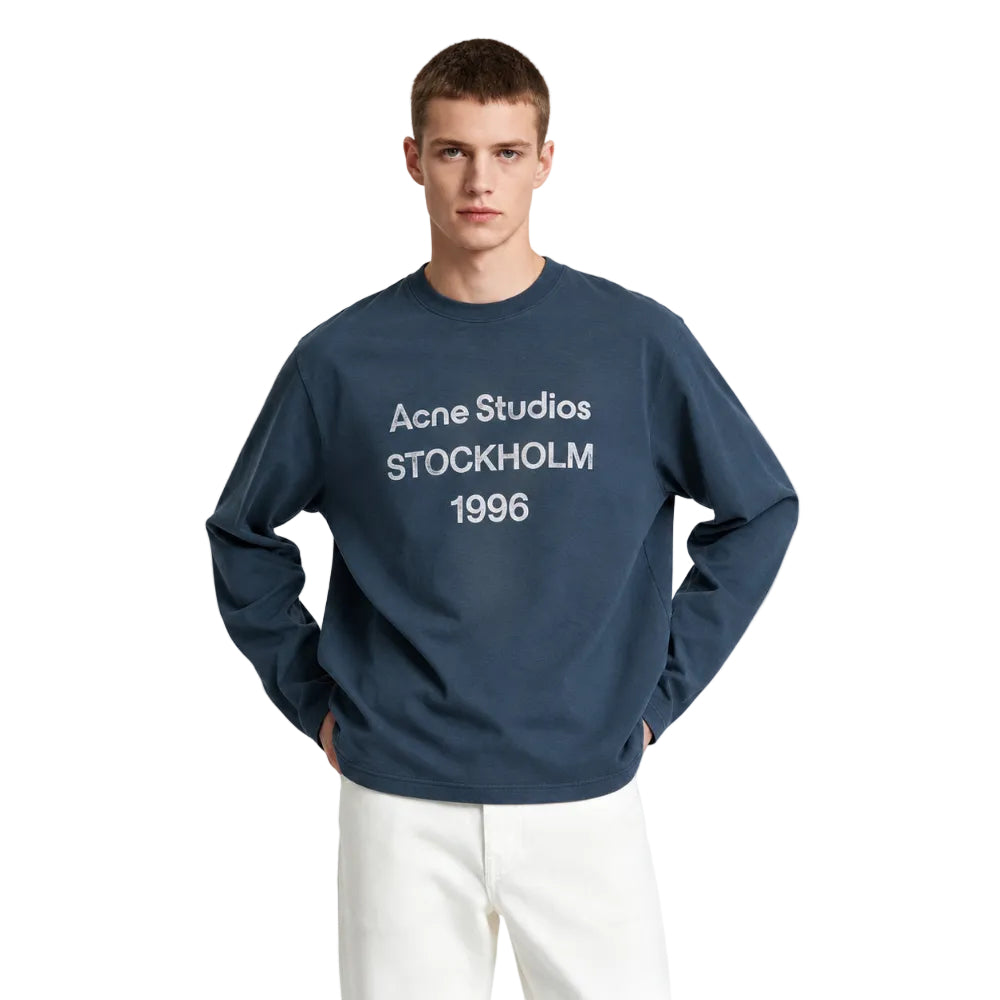 Model wearing Acne Studios Sprayed 1996 Logo T-Shirt in Deep Blue – front view highlighting the 1996 logo and relaxed long-sleeve silhouette