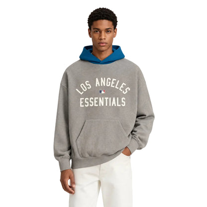 Fear of God Essentials Dodgers Sport Hoodie Concrete Heather Blue Sapphire worn by model from the front