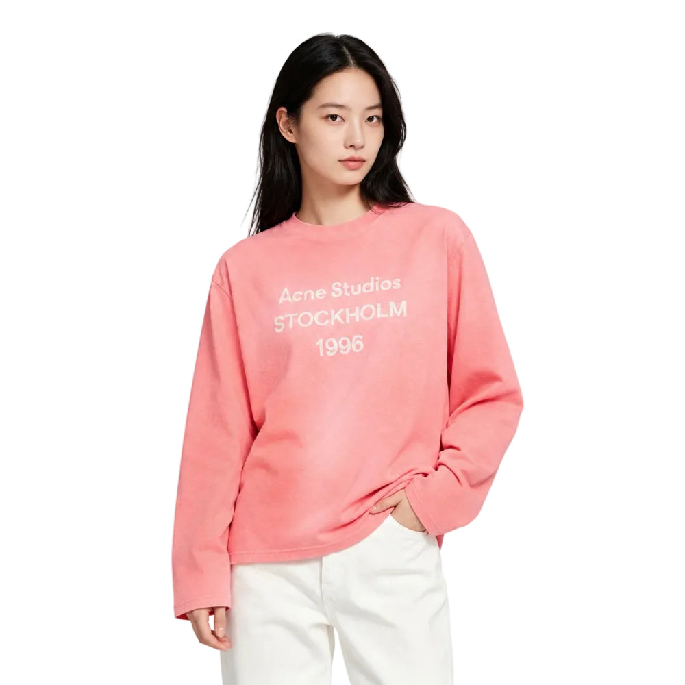 Model wearing Acne Studios Sprayed 1996 Logo T Shirt in Tango Pink – front view highlighting the chest print and relaxed silhouette